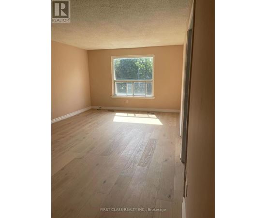 A room with wooden flooring and a window letting in sunlight.