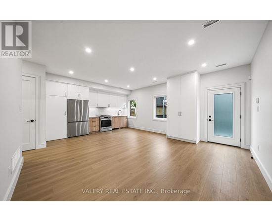 A spacious kitchen with white cabinets and a wooden floor.