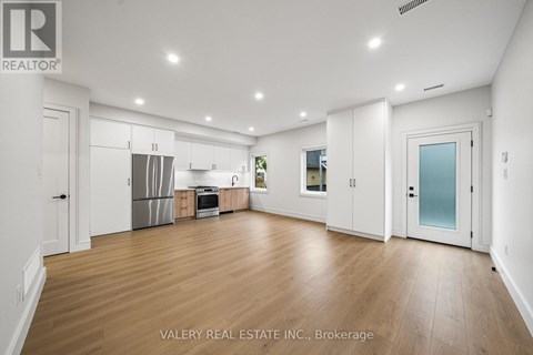 A spacious kitchen with white cabinets and a wooden floor.