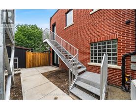 A red brick building with a metal staircase leading to a door.