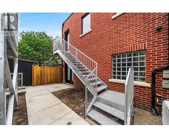 A red brick building with a metal staircase leading to a door.
