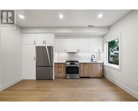 A kitchen with white cabinets and a grey fridge.