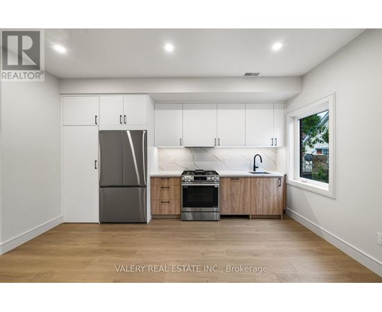 A kitchen with white cabinets and a grey fridge.