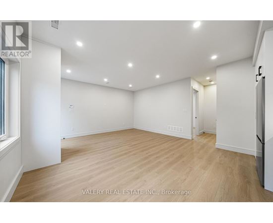 A spacious room with wooden flooring and recessed lighting.