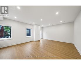 A spacious room with wooden flooring and white walls.