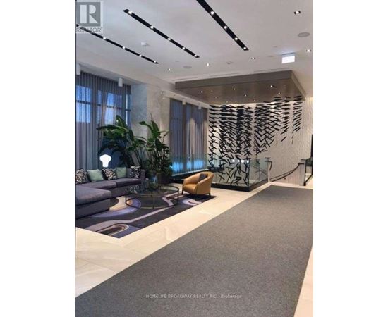 A modern living room with a grey carpet and a large abstract art piece on the wall.