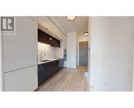 A modern kitchen with white cabinets and a wooden floor.