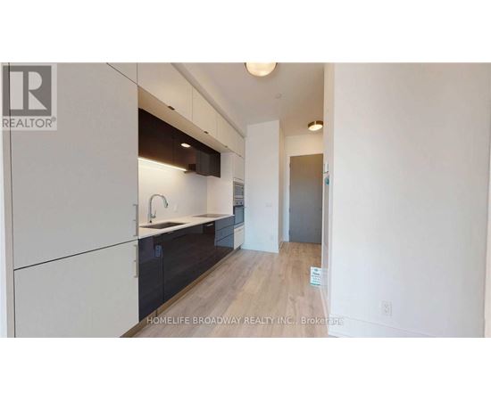 A modern kitchen with white cabinets and a wooden floor.