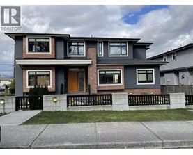 A modern two-story house with a grey and brown exterior and a black metal fence.