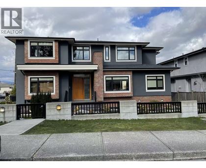 A modern two-story house with a grey and brown exterior and a black metal fence.