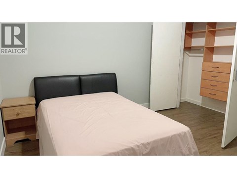 A bedroom with a bed, nightstand, and a dresser with drawers.