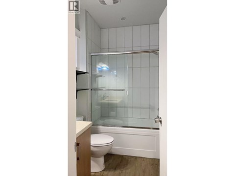 A white toilet sits next to a glass shower stall in a bathroom.