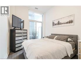 A bedroom with a large bed, a television, and a painting on the wall.