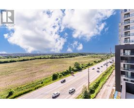 A realtor's photo of a highway with cars and a building on the right.
