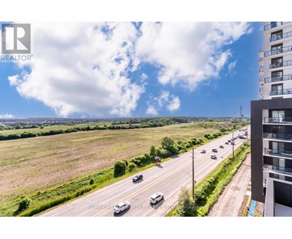 A realtor's photo of a highway with cars and a building on the right.