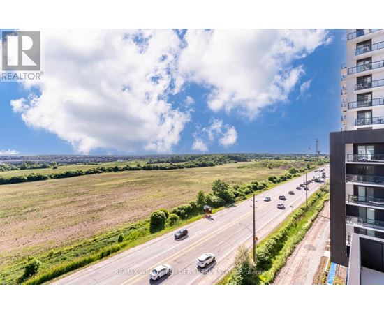 A realtor's photo of a highway with cars and a building on the right.