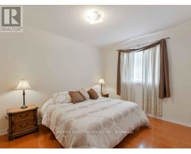 A bedroom with a bed, nightstand, and window.