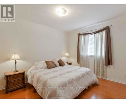 A bedroom with a bed, nightstand, and window.