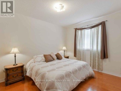 A bedroom with a bed, nightstand, and window.