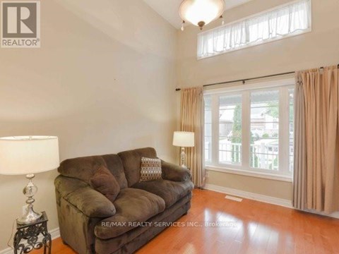 A brown couch sits in a living room with a lamp and a window.