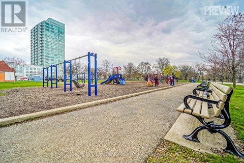 A park with a playground and a tall building in the background.