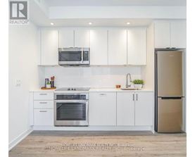 A modern kitchen with white cabinets and stainless steel appliances.