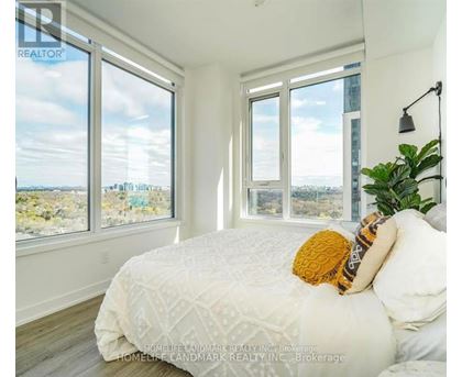 A bedroom with a large bed and a view of the city through the windows.