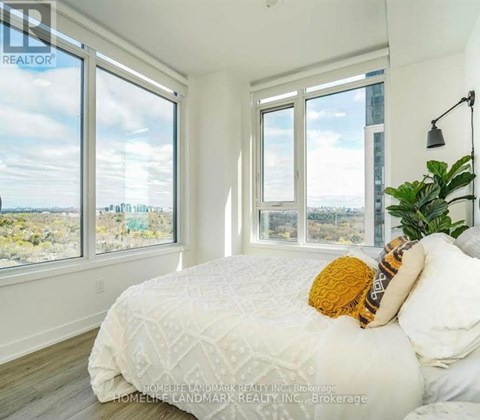 A bedroom with a large bed and a view of the city through the windows.