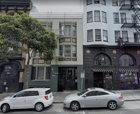 Two cars parked on the street in front of a building.