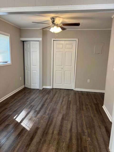 A room with a ceiling fan and wooden flooring.