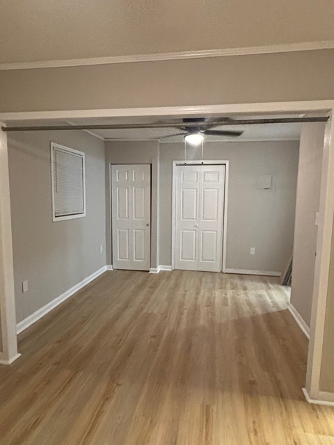 A room with a ceiling fan and wooden flooring.