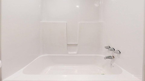 A white bathroom with a tub and faucet.