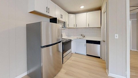 A kitchen with a stainless steel refrigerator and wooden floors.