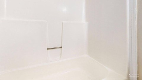 A white bathroom with a white tub and a white shower.