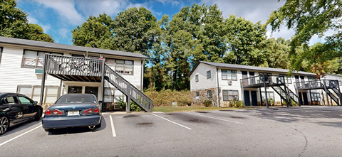 A car is parked in a parking lot in front of a white building.