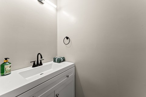 A white bathroom sink with a green towel and a green bottle.