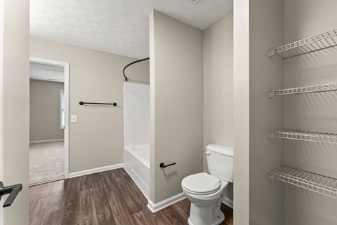A white toilet sits in a small bathroom with a walk-in shower.