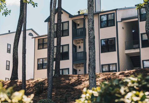 A building with balconies is surrounded by trees.