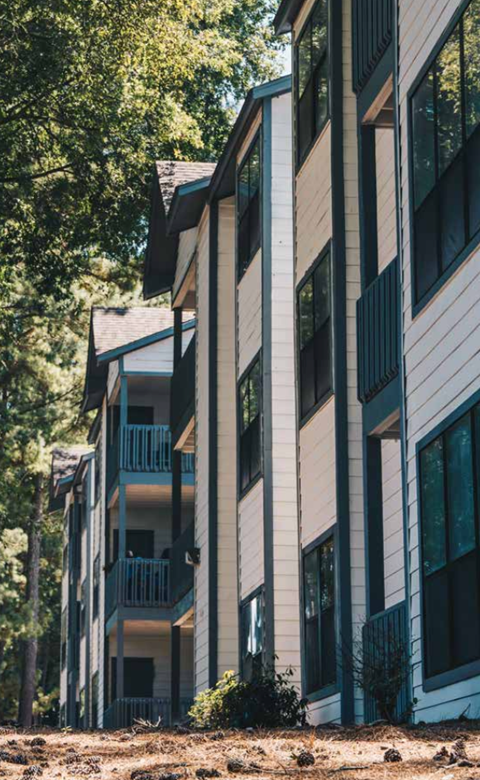 A building with balconies and windows is surrounded by trees.