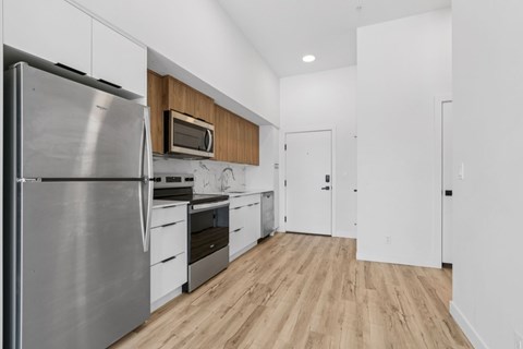 A modern kitchen with a stainless steel refrigerator and wooden cabinets.
