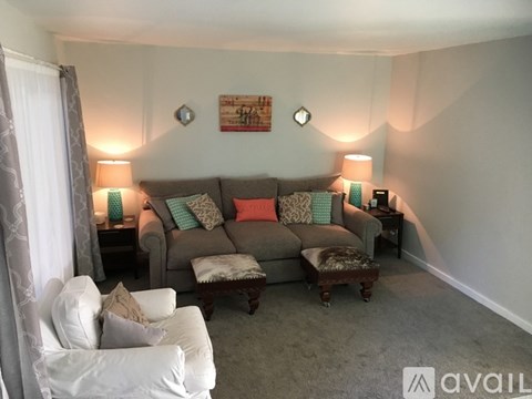 A living room with a grey couch, a white chair, and two lamps.