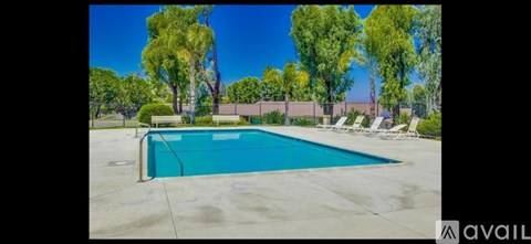 A pool surrounded by trees and chairs.