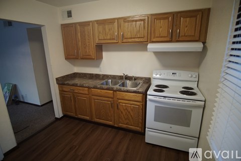 A kitchen with wooden cabinets and a white stove top oven.