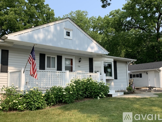 A house with a flag on the porch and a white picket fence.