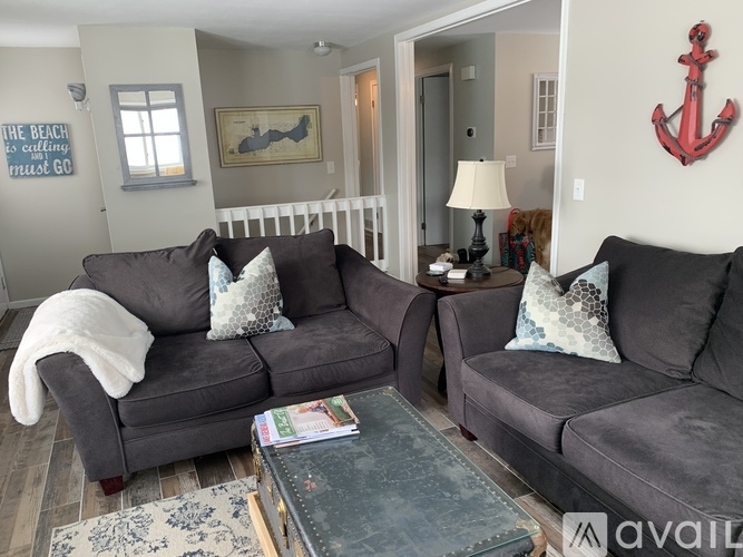 A living room with a grey couch and a red anchor on the wall.
