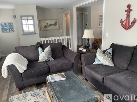 A living room with a grey couch and a red anchor on the wall.