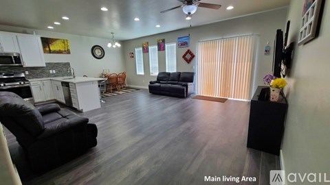 A living room with a black couch and a wooden floor.