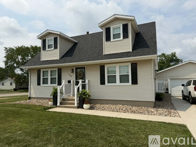 A house with a grey roof and white walls is shown with a car parked in the driveway.