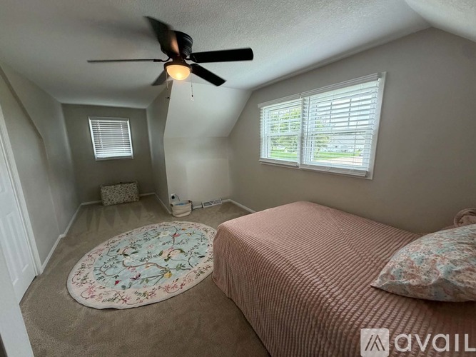 A bedroom with a bed, a ceiling fan, and a rug.