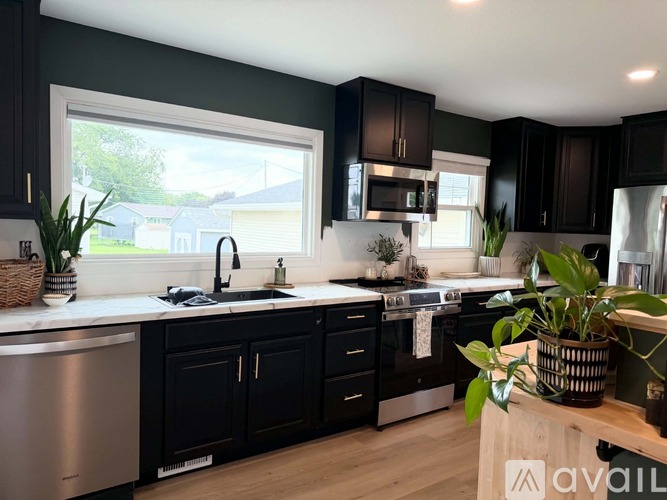A kitchen with black cabinets and a stainless steel dishwasher.